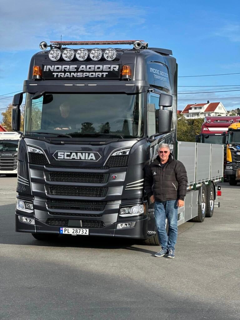 Rune THorsen foran en av lastebilene sine. Foto.