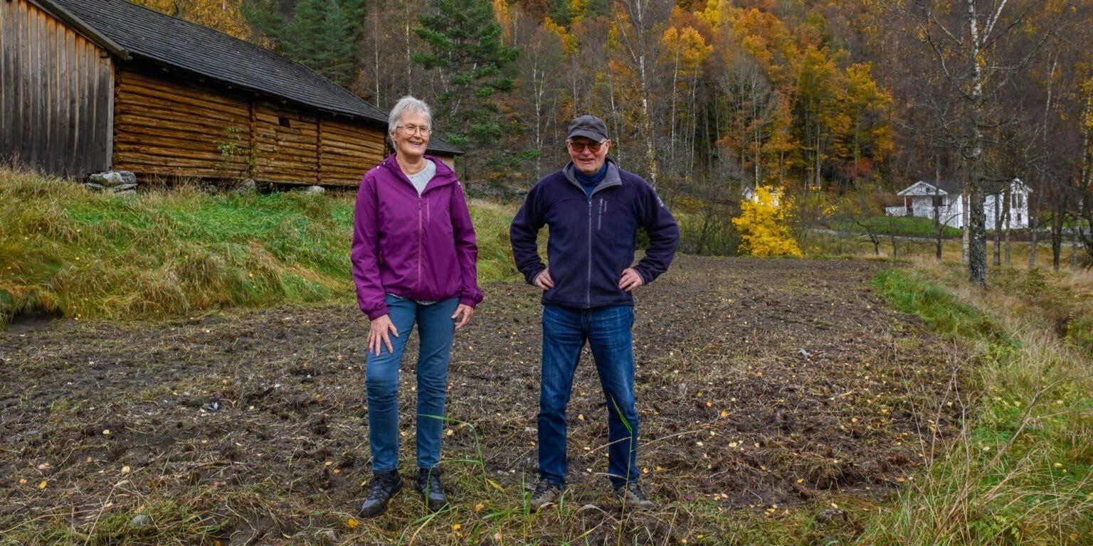 Rigmor Flåt og Nils Gjermund Østerhus med parsellhagen bak seg. Foto.