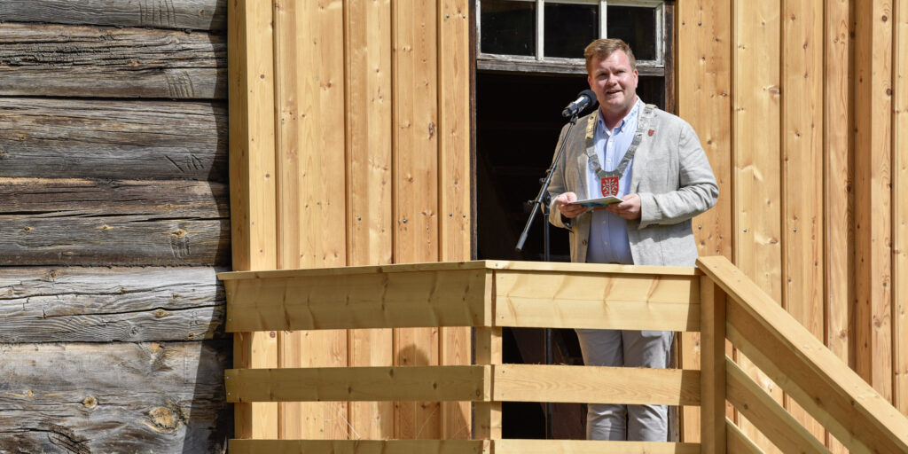 Fylkesvaraordførar Rune Andre Frustøl talar frå trappa på stogehuset i Tveitetunet. Foto: