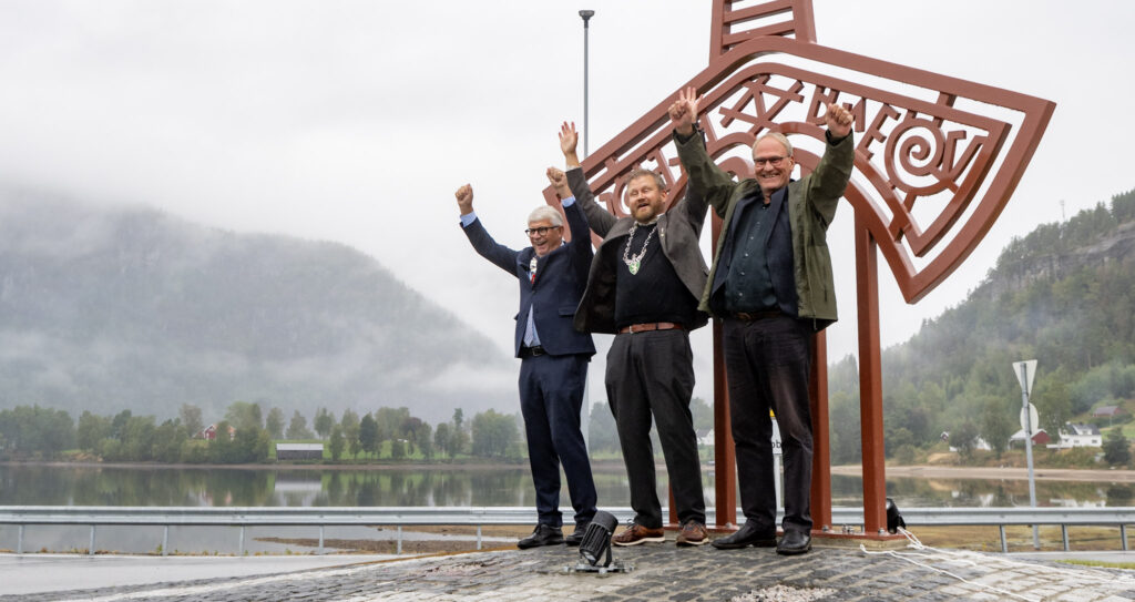 Jubel for avdukinga av Langeidsverdet på Bygland 11. september 2026. Frå venstre fylkesordførar Arne Thomassen, ordførar Runar Granheim og ass. direktør ved Kulturhistorisk museum Karl Kallhovd. Foto foran den store kopien av Langeidsverdet.